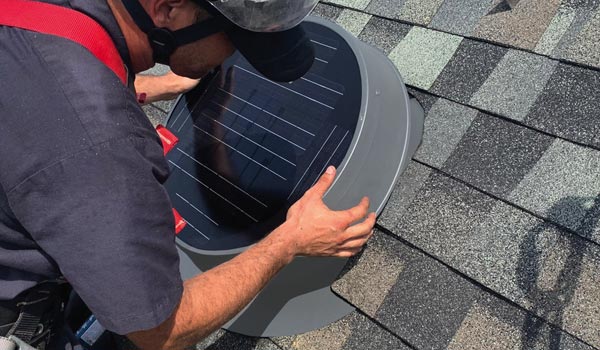 Natural Light installer on roof attaching solar attic fan mobile