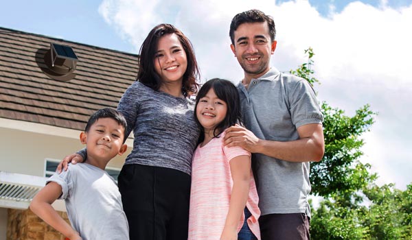 Family in front of home with Natural Light solar attic fan installed mobile