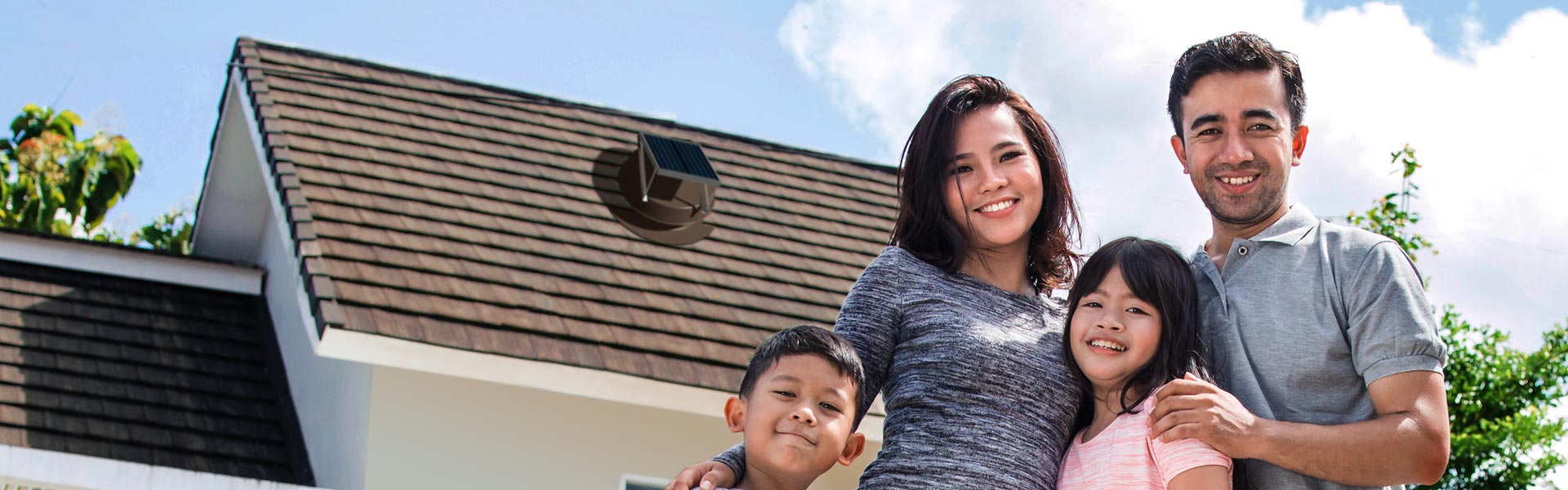 Family in front of home with Natural Light solar attic fan installed