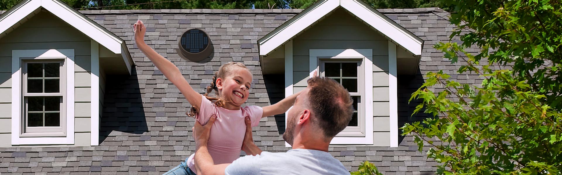 father and daughter in front of home with Natural Light solar attic fan installed